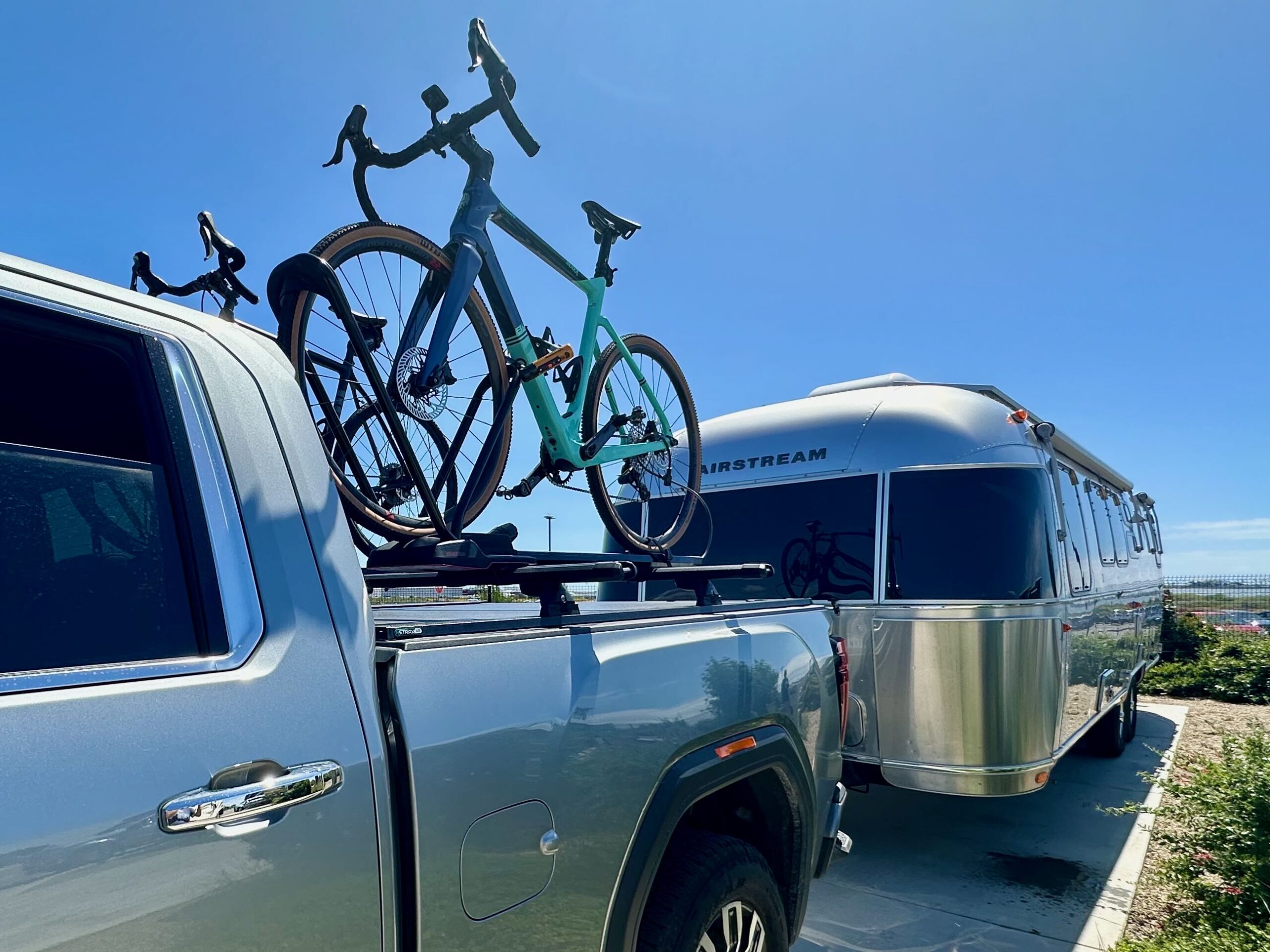 Bikes mounted above the bed of a pickup truck with an Airstream in the background
